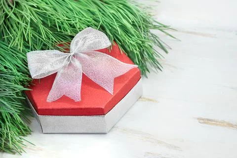 Red gift box with silver bow with spruce branches on white table. Christmas Stock Photos