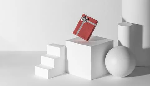Red gift box with silver ribbon among white 3d shapes Stock Illustration