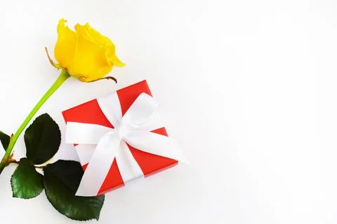 Red gift box with white bow and yellow rose on a white background. Copy space Stock Photos