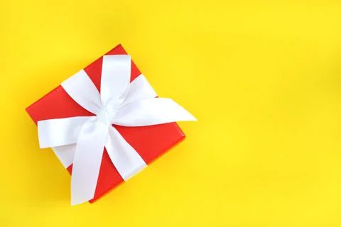 Red gift box with white bow  on yellow background. Copy space. Foto stock
