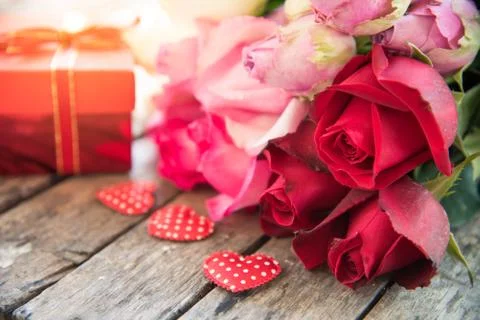 Red gift boxes, red hearts and roses are placed on a wooden floor. Stock Photos