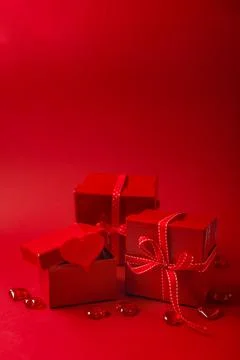 Red gift boxes with red ribbon and decorative hearts on red background Stock Photos