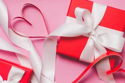 Red gift boxes tied with a white ribbon, two paper hearts Stock Photos