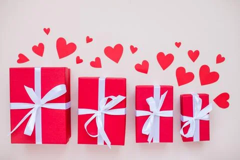 Red gift boxes of various sizes tied with a white satin ribbon and red hearts Stock Photos