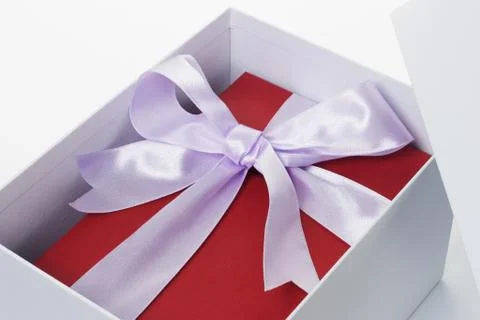 Red giftbox with bow ribbon inside open white box Foto stock