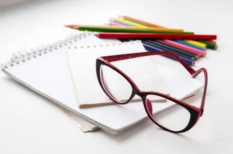 Red glasses on the notebook and colored pencils Stock Photos