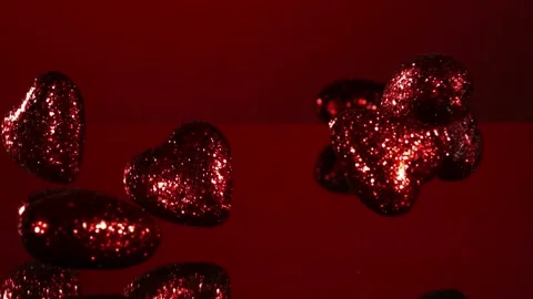 Red glitter hearts fall on red surface Stock Footage 327178326