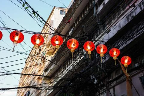 Red globe lanterns hanging on wire with background of old buildings. Stock Photos