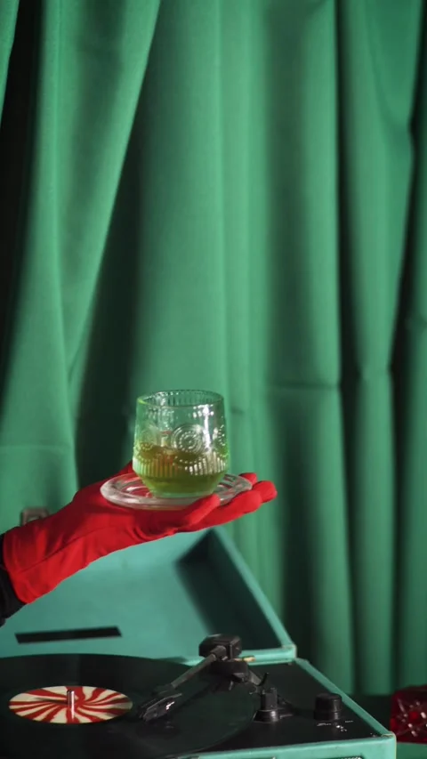 Red gloved hand presenting amber liquor glass by retro turntable Stock-Footage 345856952