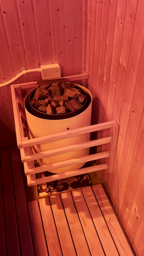 Red glow from light on wood panelling and igneous sauna stones Stock Footage 344010577