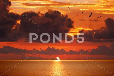 Red glowing sunset above serene sea Stock Photos