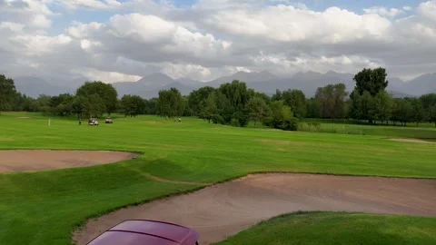 Red golf cart in front of the golf field with mountains on background Stock Footage 326625862