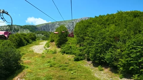Red gondolas glide above green hills. Savin Kuk peak, Montenegro 库存影片 342981986