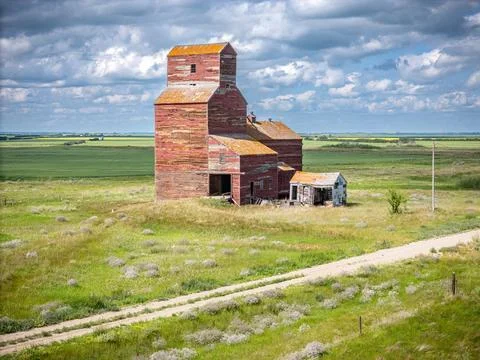 Red grain elevator sits in a field with a road in front of it Stock Photos