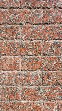 Red granite stone wall with rectangular blocks and speckled texture Stock Photos