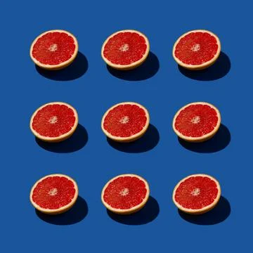 Red grapefruit sunlit square pattern arrangement on a deep blue background. Stock Photos