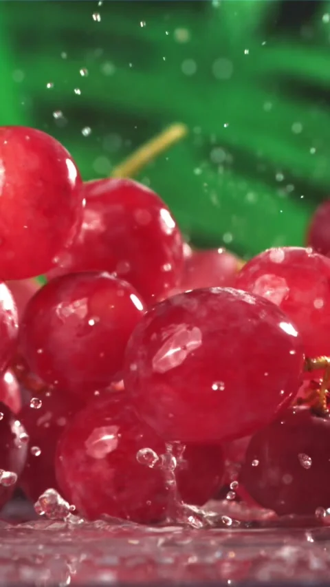 Red grapes fall with splashes on a wet table. Filmed on a high-speed camera at Stock Footage 335322261