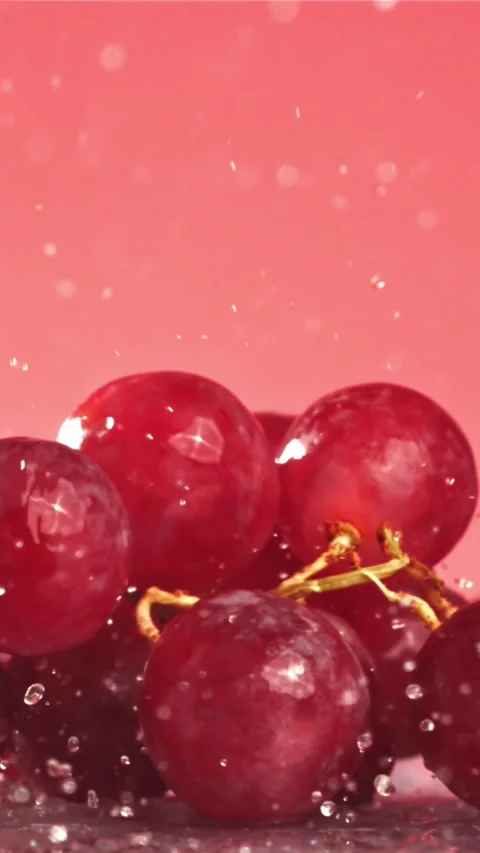 Red grapes fall with splashes on a wet table. Filmed on a high-speed camera at Stock Footage 335322300