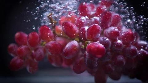 Red grapes fall into water with splashes super slow motion shot Video stock 122979652