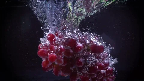 Red grapes fall into water with splashes super slow motion shot Video stock 122982063