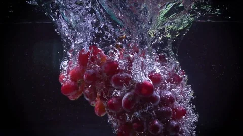 Red grapes fall into water with splashes super slow motion shot Video stock 122982065
