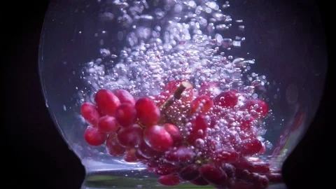 Red grapes fall into water with splashes super slow motion shot Video stock 122982100