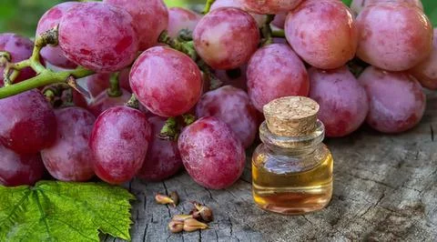 Red grapes with small bottle of grape seed oil on wood Stock Photos