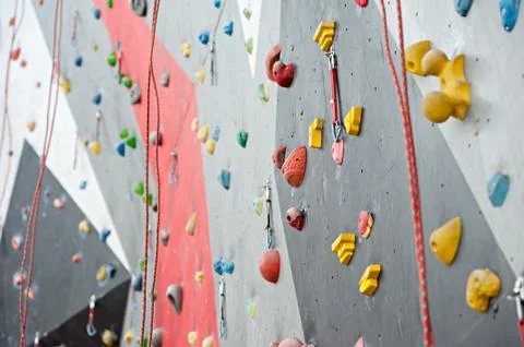 Red-gray wall of climbing wall, with ledges and ropes with carbines Stock Photos