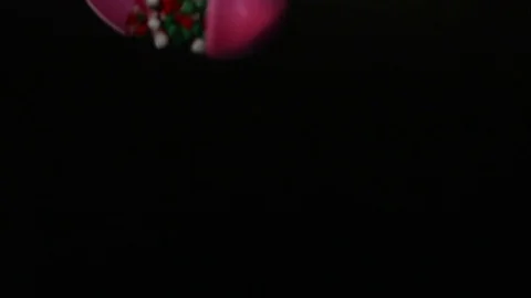 Red Green And White Candy Spills Out Of Pink Egg On Black Stock Footage 70333314