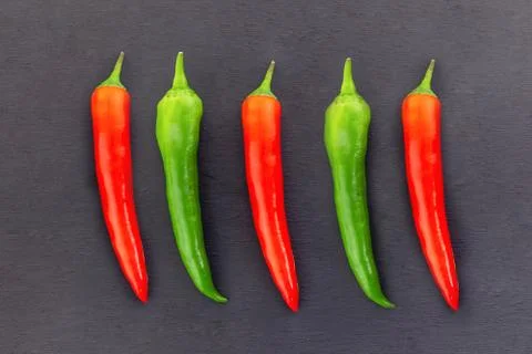 Red green parallel pod of sharp pepper repeating contrasting on a black backg Stock Photos