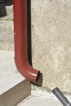 Red gutter downspout on a textured wall Stock Photos