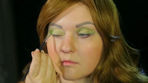Red-haired actress in the dressing room makes eye makeup green shadows preparing 库存影片 107786436