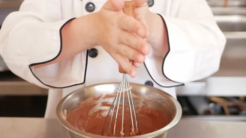 Red-haired boy in chef's costume cooks pancakes in kitchen, kneads dough Stock Footage 197066189