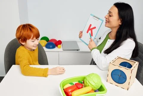 Red-haired boy during speech therapy session. Speech therapist teaching child Fotos Stock