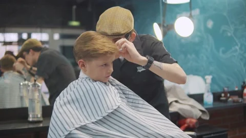 A red-haired boy gets his hair cut by a stylish hairdresser. Stock Footage 143383882