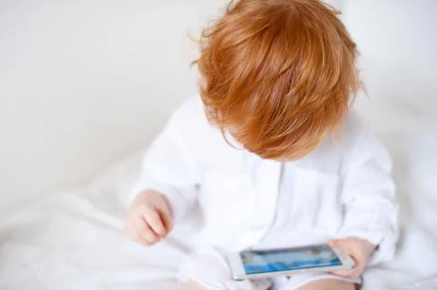 Red-haired boy looking into the phone Stock Photos