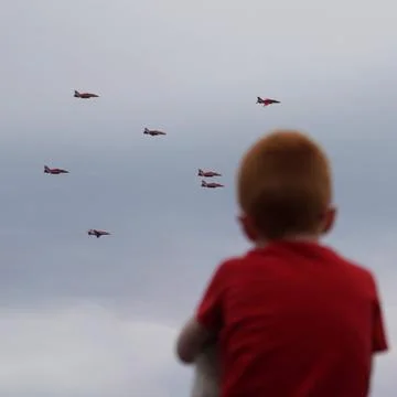 Red haired boy with read t-shirt watching the red jet air aeroplanes on father's Stock Photos