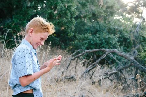 Red Haired Boy Smiles While Looking At His Hand After A Fall Stock Photos