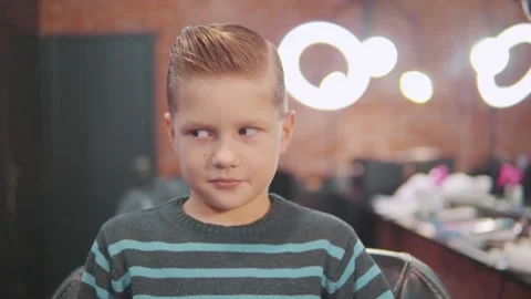 Red-haired boy with stylish styling sits in the barbershop. Video stock 143385145