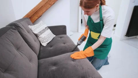 A red-haired cleaning lady from a cleaning service uses a vacuum cleaner to clea Stock Footage 301516650