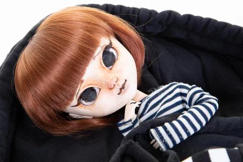 Red-haired doll lying in black cap of child girl Stock Photos