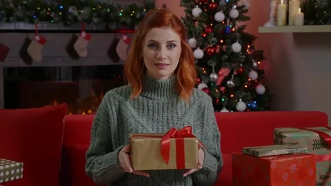 A red-haired female looking up the camera gives Christmas gift to family friends Stock Footage 314781843