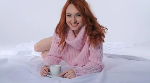 Red-haired girl drinking coffee lying on the bed Stock Footage 35400688