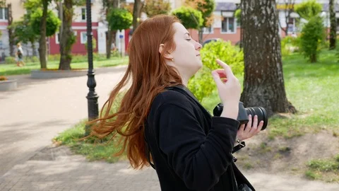 Red-haired girl is working with a camera. Sunny day Video stock 113637312