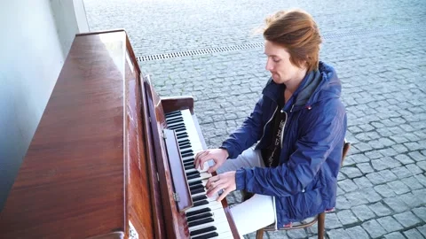 Red-haired guy playing the piano in a blue jacket on the street 動画素材 163350993