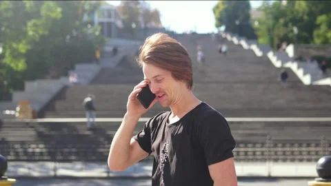 Red-haired guy talking on the phone and waving to someone Stock-Footage 163364063