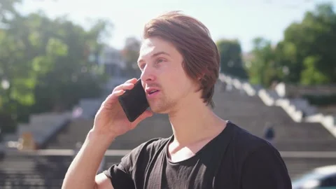 Red-haired guy talking on the phone and waving to someone Stock-Footage 163364228
