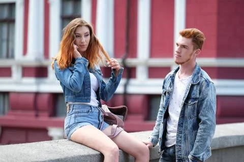 A red haired guy is waiting for a red haired girl talking on her mobile phone Stock Photos