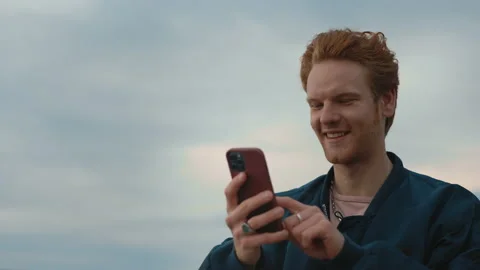 Red haired guy walking on street with mobile in hands Stock Footage 161788397