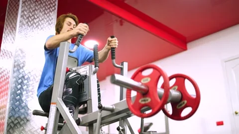 Red-haired guy worked out the training apparatus in the red gym.pull a weight Stock-Footage 163460263